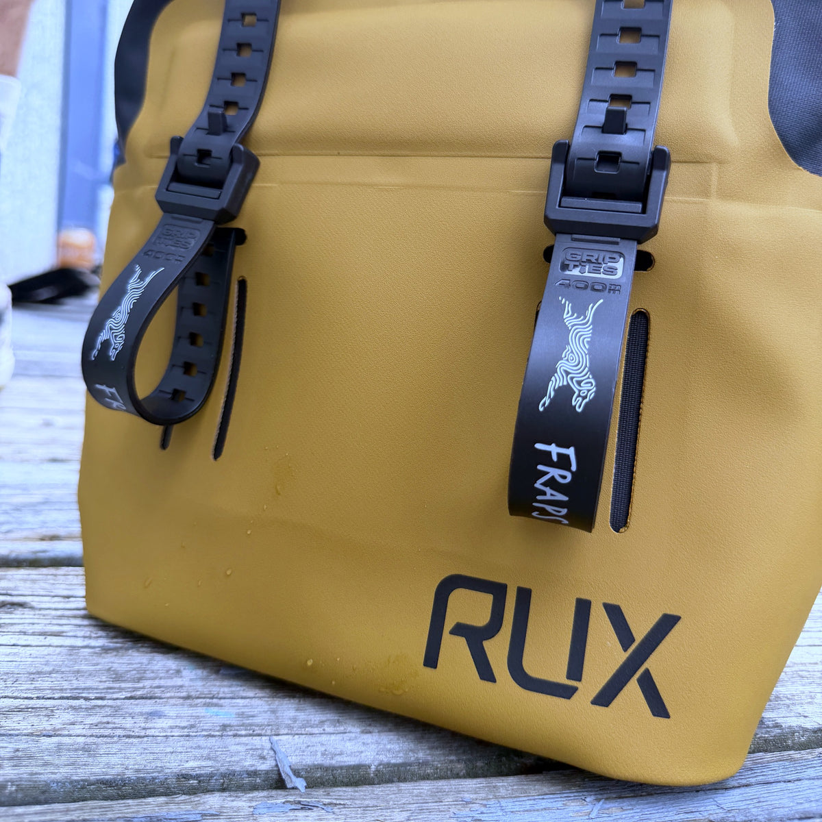 Two FRAPS STRAPS on a RUX bag on a wooden deck